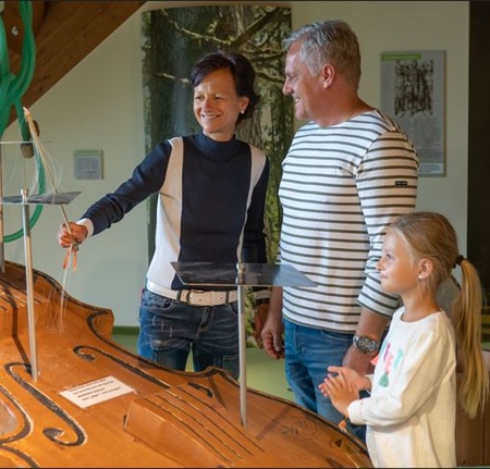 Familie betrachtet eine interaktive Ausstellung an einem Musikinstrument im Museum.