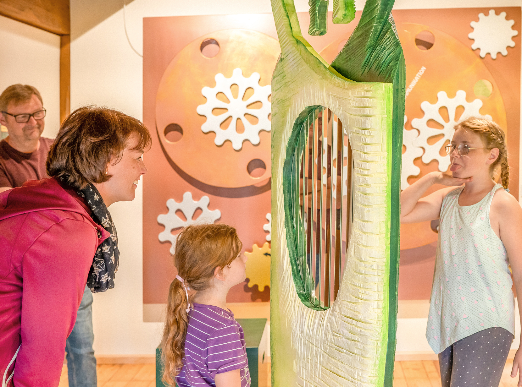 Familie betrachtet eine interaktive Kunstinstallation in einer Galerie, während zwei Kinder spielerisch interagieren.