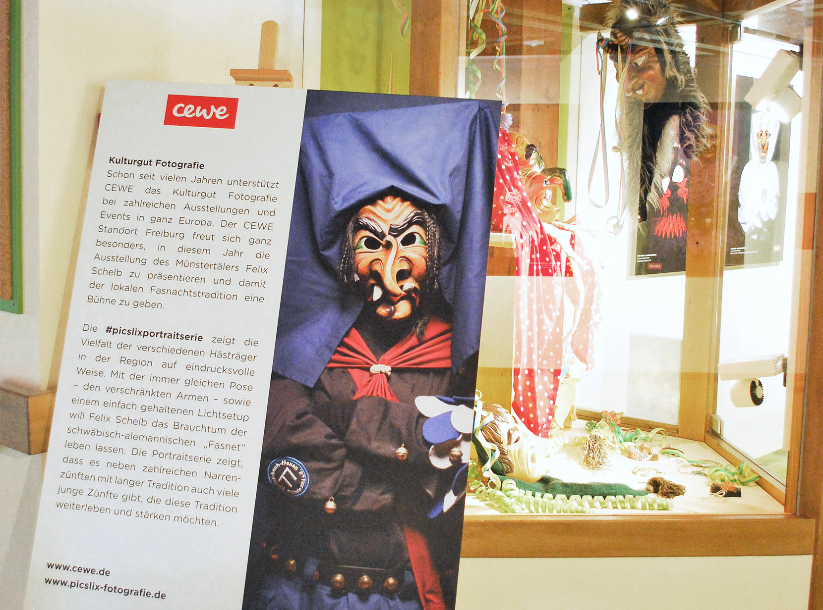 Ein Plakat mit einer Fasnachtsmaske und Informationen zur Kulturfotografie, umgeben von Ausstellungselementen.